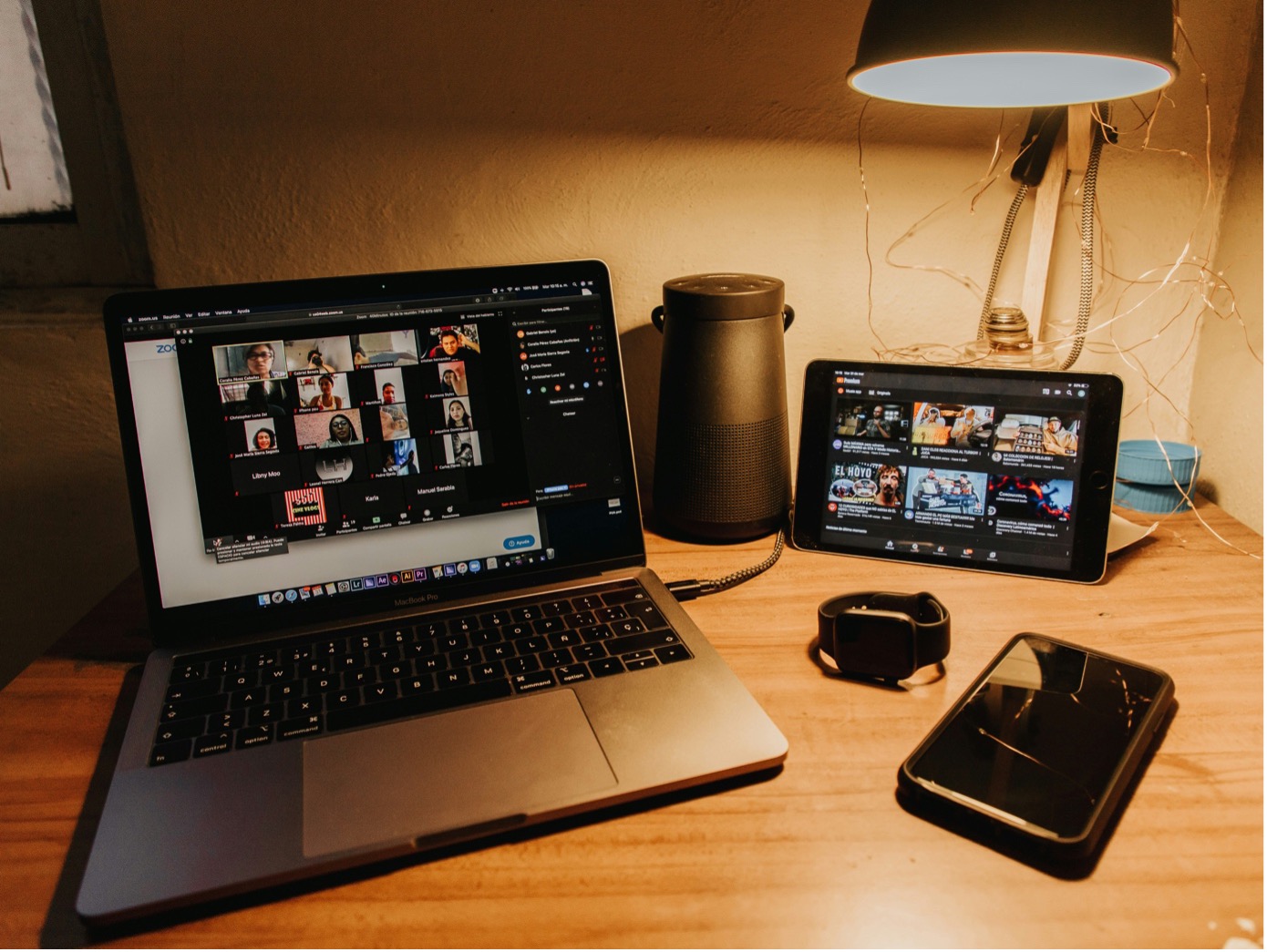 Computer auf dem gerade ein Videochat stattfindet. Daneben weitere technische Geräte, wie ein Smartphone und ein Tablet.