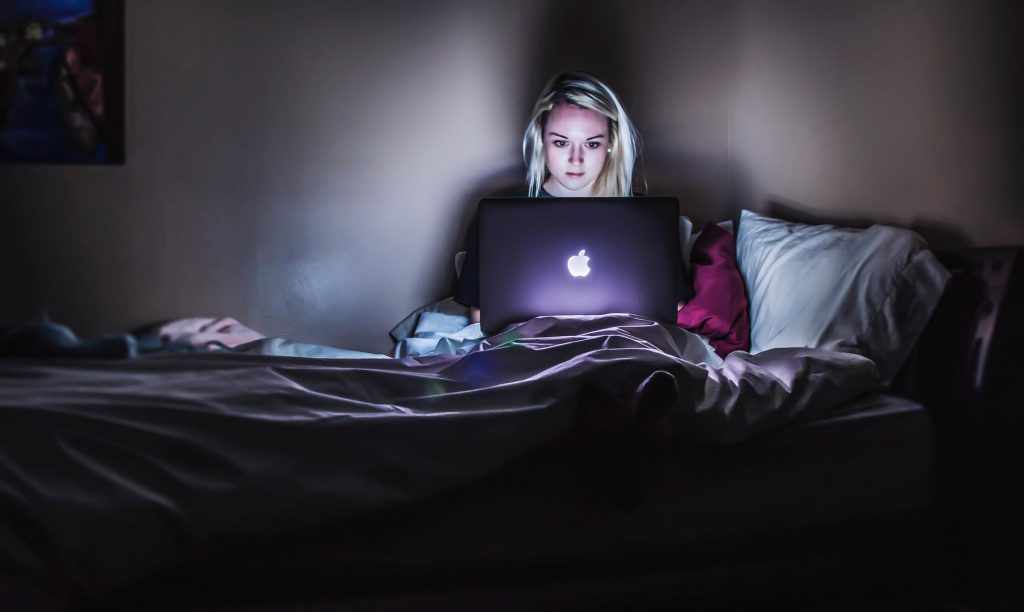 Mädchen im Bett vor dem Laptop im Dunklen