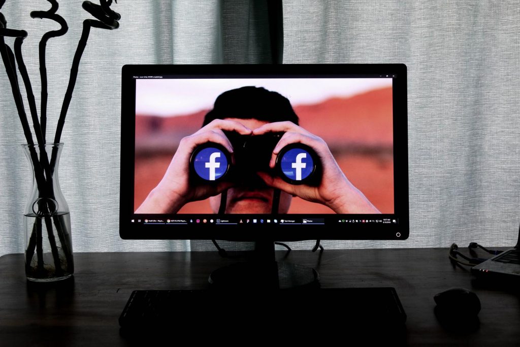 Mann mit Facebook Fernglas auf einem Monitor